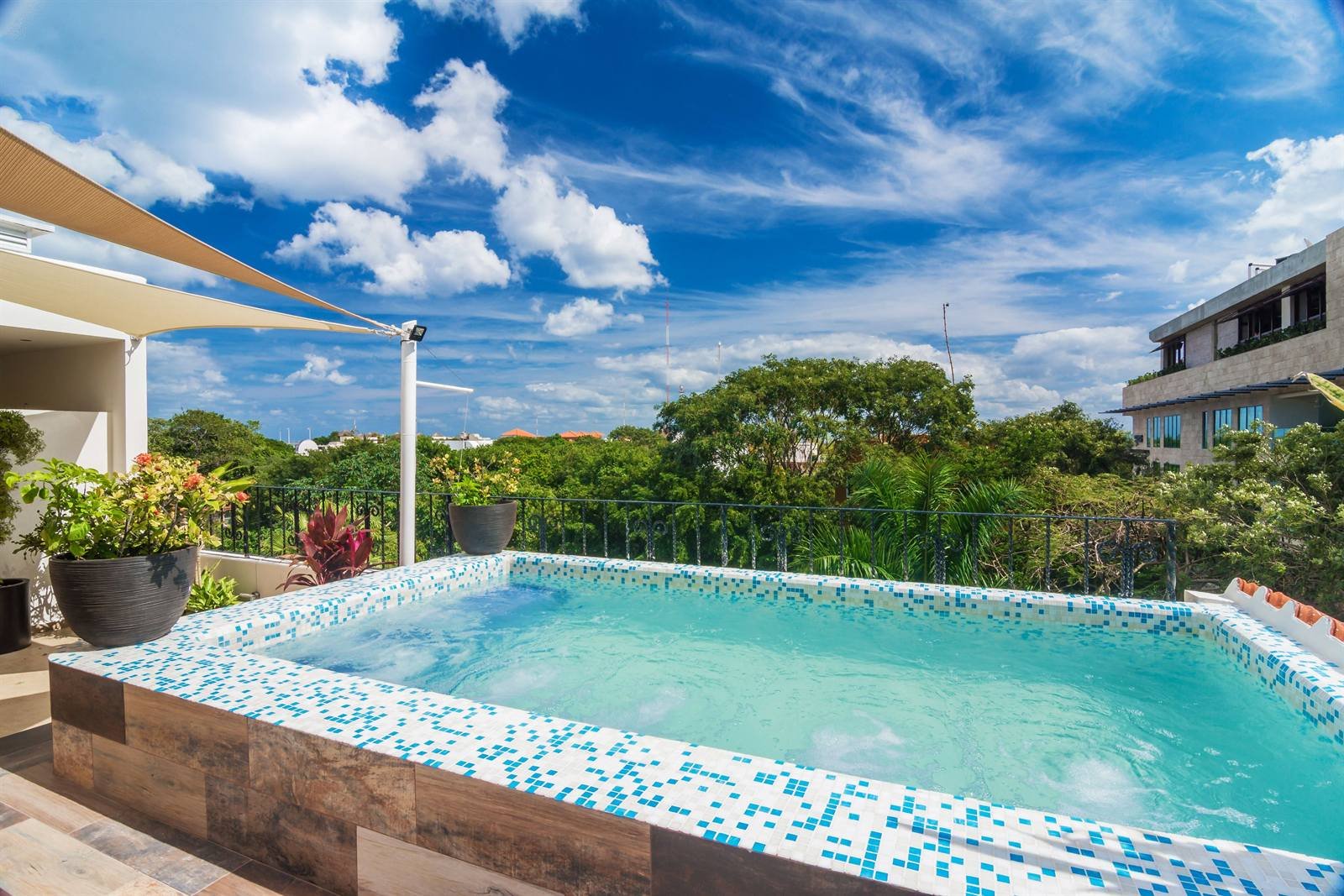 Suites Corazón: blue-tiled pool framed by a wooden deck